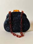 Borsa vintage in pelle nera goffrata con chiusura a scatto e catena in resina ambrata