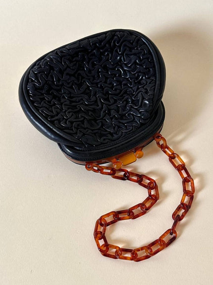 Borsa vintage in pelle nera goffrata con chiusura a scatto e catena in resina ambrata