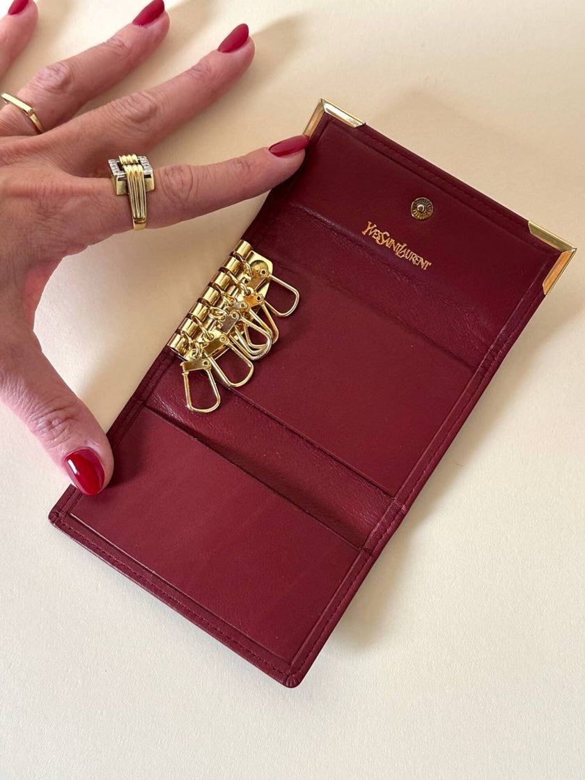 Portachiavi trifold Yves Saint Laurent in pelle rosso granata con dettagli dorati e logo YSL a caldo