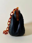 Borsa vintage in pelle nera goffrata con chiusura a scatto e catena in resina ambrata