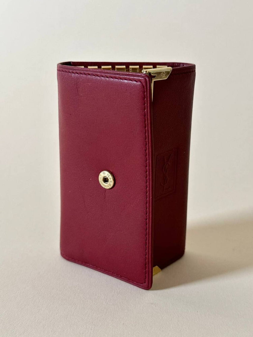 Portachiavi trifold Yves Saint Laurent in pelle rosso granata con dettagli dorati e logo YSL a caldo