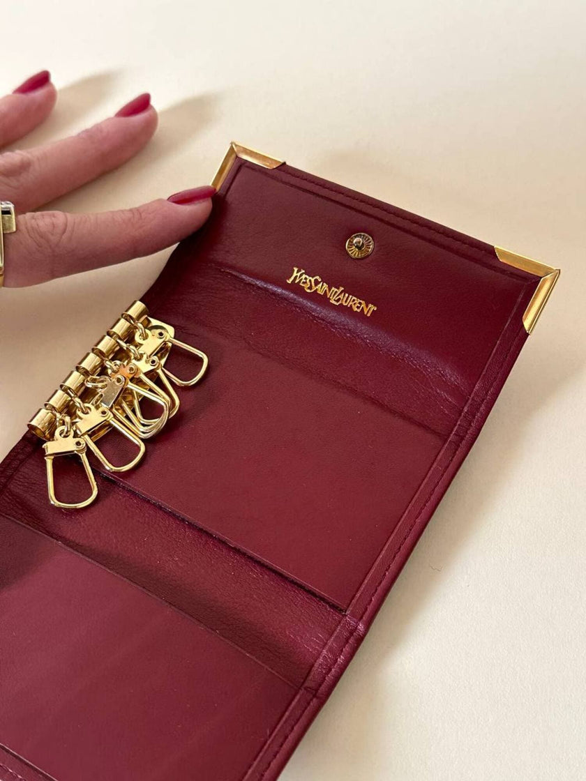 Portachiavi trifold Yves Saint Laurent in pelle rosso granata con dettagli dorati e logo YSL a caldo