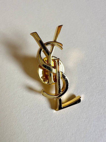 Spilla logo YSL dorata con dust nera “Yves Saint Laurent”
