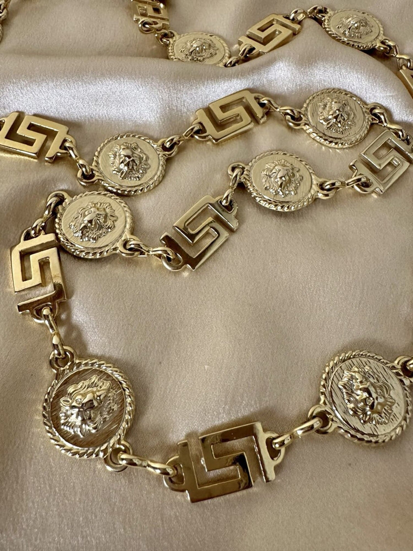 Cintura/collana dorata composta da greche e teste di leone