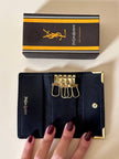 Porte-clés trifold Yves Saint Laurent en cuir noir avec détails dorés et logo YSL embossé