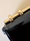 Borsa in vernice nera con manico design in metallo oro
