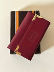 Portachiavi trifold Yves Saint Laurent in pelle rosso granata con dettagli dorati e logo YSL a caldo