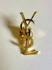 Spilla logo YSL dorata con dust nera “Yves Saint Laurent”