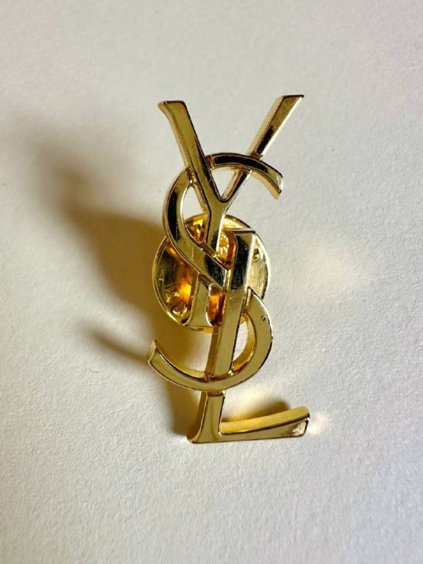 Spilla logo YSL dorata con dust nera “Yves Saint Laurent”