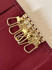 Portachiavi trifold Yves Saint Laurent in pelle rosso granata con dettagli dorati e logo YSL a caldo