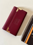 Portachiavi trifold Yves Saint Laurent in pelle rosso granata con dettagli dorati e logo YSL a caldo