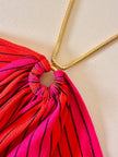Abito midi a righe nei toni del fucsia e rosso con collana gioiello “Armonie”
