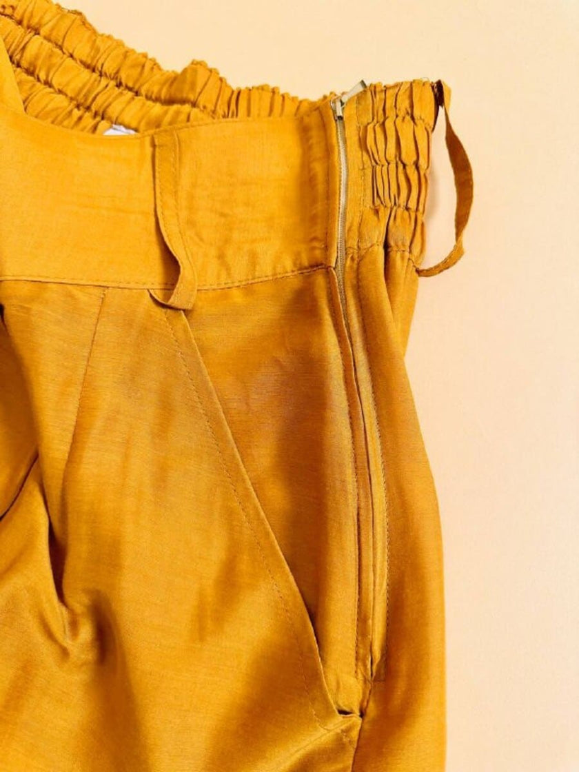 Pantalone chino con piega asimmetrica e soffietto plissé giallo indiano