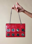 Borsa rossa in coccodrillo con borchie argento e tracolla metallica “Nicolette”