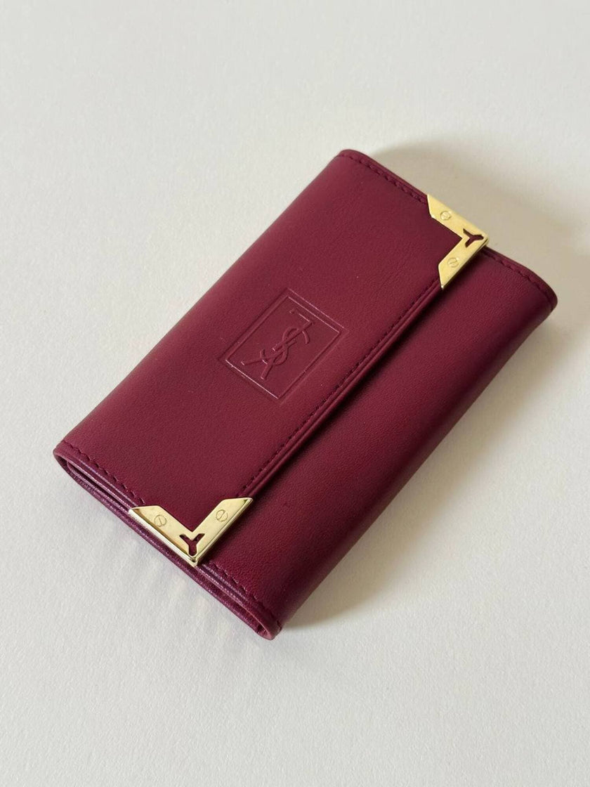 Portachiavi trifold Yves Saint Laurent in pelle rosso granata con dettagli dorati e logo YSL a caldo