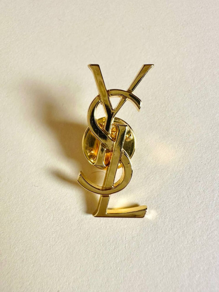 Spilla logo YSL dorata con dust nera “Yves Saint Laurent”