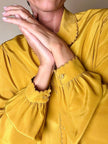 Camicia sartoriale in seta color senape con profili smerlati